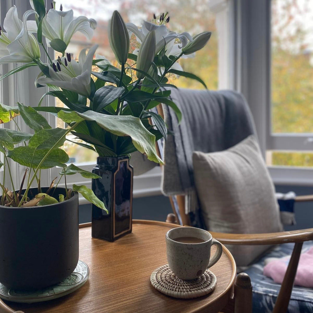 handmade ceramic vase on a table with bunch of lilies. 