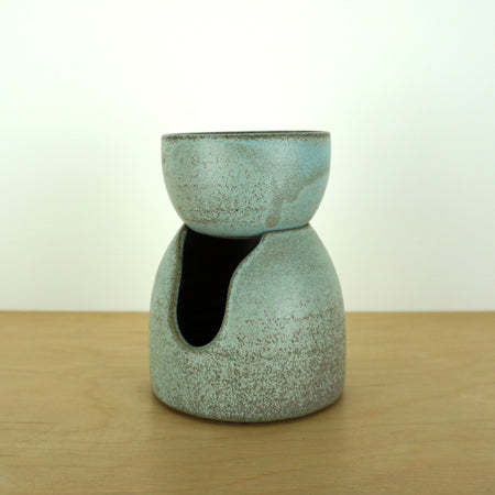handmade oil burner sitting on a birch ply table with a white background.