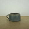 elegant handmade ceramic mug on a wooden table with a white background. 