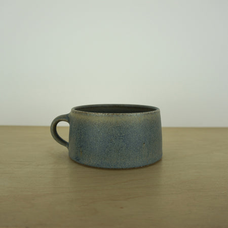 elegant handmade ceramic mug on a wooden table with a white background. 
