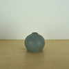 a small blue grey coloured handmade ceramic vase on a table. 