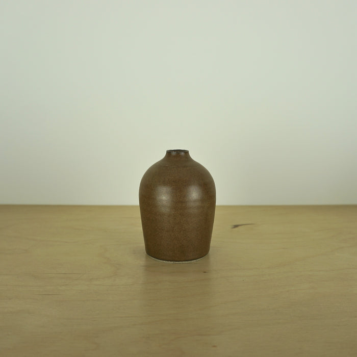 a small brown / tamba coloured handmade ceramic vase on a table. 