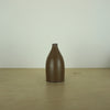 a small brown/tamba coloured handmade ceramic vase on a table. 