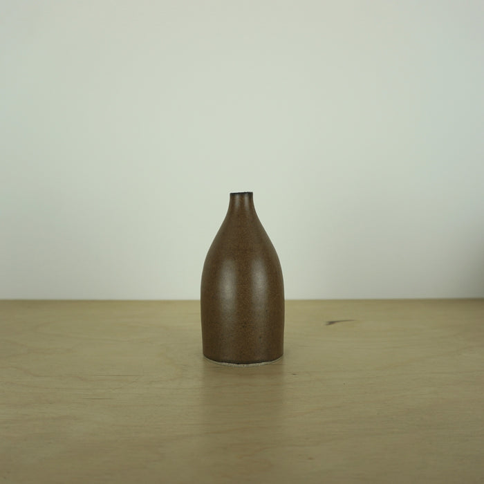 a small brown/tamba coloured handmade ceramic vase on a table. 