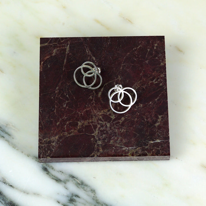 Pair of silver ring earrings on a maroon marble surface | Scarlett French | Shop Fodder