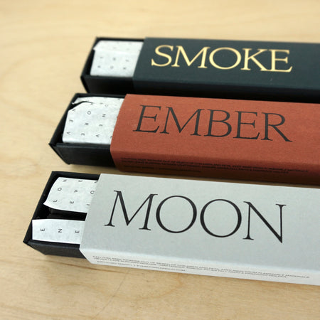 three open packets of incense sticks on a table. one called moon, one called ember and one called smoke. 