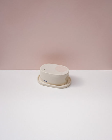 Round white object on a white surface with a pink background . Brutes Ceramics | Inlay Butter Dish | Fodder