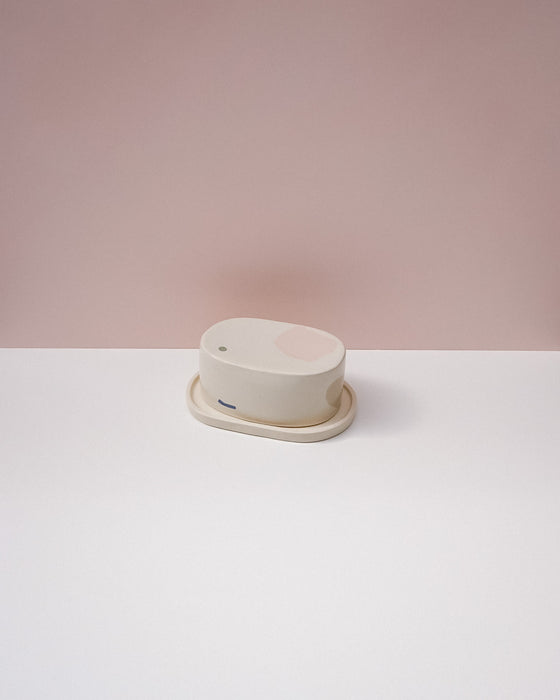 Round white object on a white surface with a pink background . Brutes Ceramics | Inlay Butter Dish | Fodder