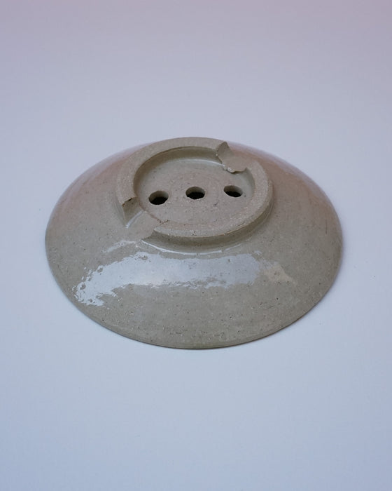 Round ceramic object with three holes on a white background. Soap Dish, Cara Guthrie Ceramics. Fodder