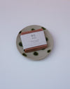 Bar of soap with a label on a ceramic plate against a white background. Cara Guthrie Ceramics. Fodder