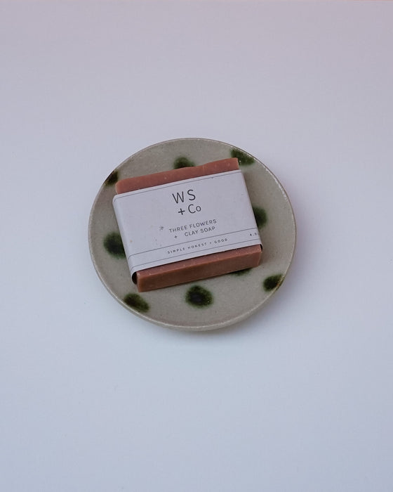 Bar of soap with a label on a ceramic plate against a white background. Cara Guthrie Ceramics. Fodder