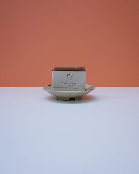 Bar of soap on a white plate with 'WS & Co' packaging against an orange background. Cara Guthrie Ceramics. Fodder