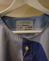 A close-up of a Carolina Dickinson shirt hanging on a white hanger, showing a blue and white gingham pattern with a solid navy blue panel and a single button. Caroline Dickinson Shirt | Fodder
