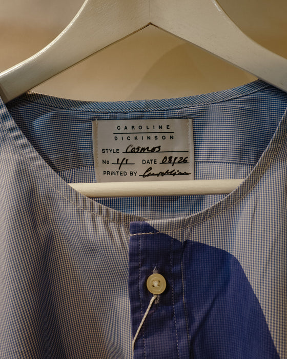 A close-up of a Carolina Dickinson shirt hanging on a white hanger, showing a blue and white gingham pattern with a solid navy blue panel and a single button. Caroline Dickinson Shirt | Fodder