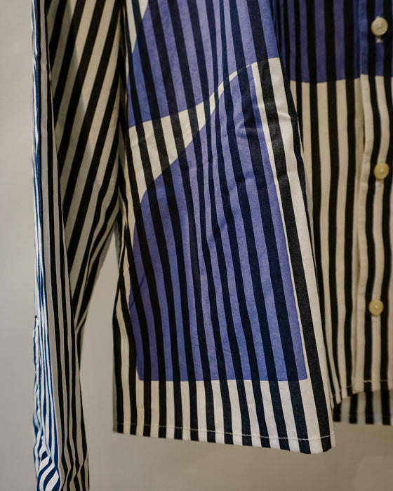 Close-up of a striped button-up shirt with navy, blue, cream, and black vertical stripes, featuring a pocket and light-colored buttons. Caroline Dickinson Shirt | Fodder