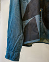 A close-up of a long-sleeve button-up shirt featuring a geometric patchwork pattern of blue denim and dark charcoal grey fabric panels, with gold buttons. Caroline Dickinson Shirt | Fodder