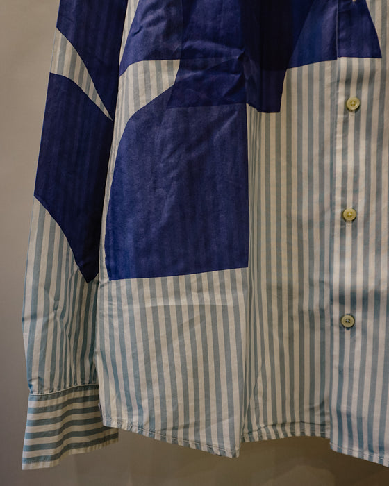 A close-up of a long-sleeve button-up shirt with a patchwork design combining blue solid panels and light blue and white vertical stripes. Caroline Dickinson Shirt | Fodder