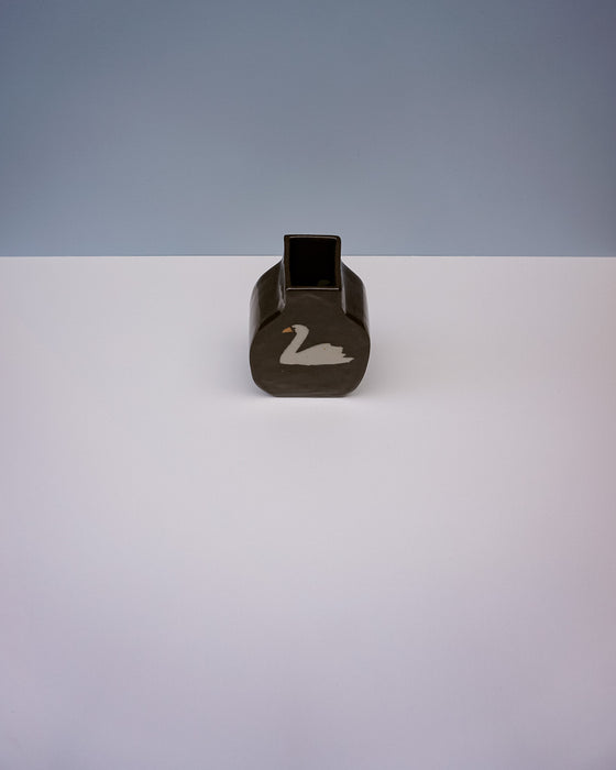 Black rectangular object with a white swan design on a white surface and gray background. Nerikomi Vase | Fern Taylor | Shop Fodder