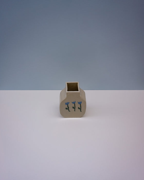Small beige ceramic vase with blue floral design on a white surface and light gray background. | Tulip Vase | Nerikomi | Fern Taylor | Shop Fodder