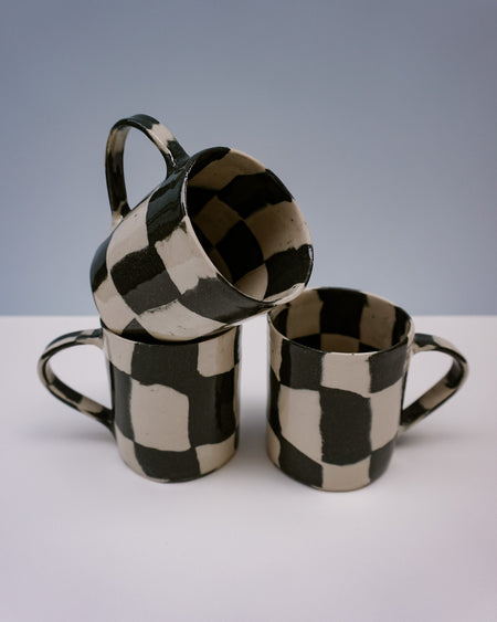Three ceramic mugs with black and white checkered pattern on a light grey background. Checkerboard Nerikomi Ceramic Mug | Fern Taylor | Kentish Town Stores