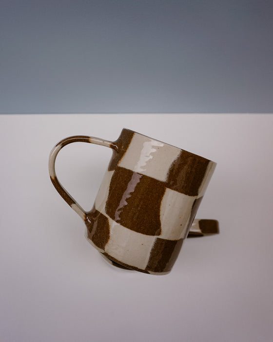 Ceramic mug with brown and beige checkered pattern on a white surface with gray background. Checkerboard Nerikomi Ceramic Mug | Fern Taylor | Kentish Town Stores