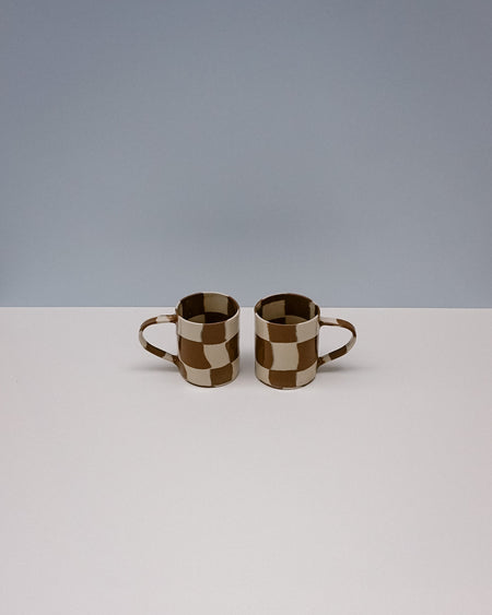 Two checkered ceramic mugs on a white surface with a gray background. Checkerboard Nerikomi Ceramic Mug | Fern Taylor | Kentish Town Stores