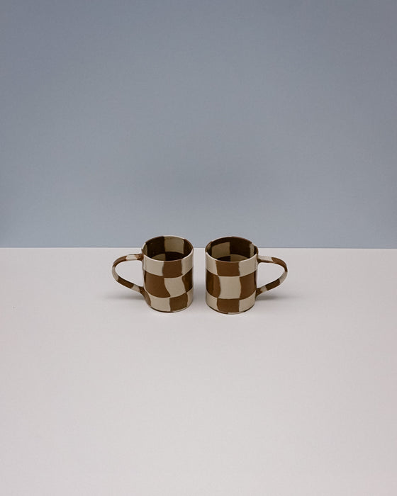 Two checkered ceramic mugs on a white surface with a gray background. Checkerboard Nerikomi Ceramic Mug | Fern Taylor | Kentish Town Stores