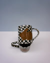 Ceramic mug with checkered pattern and brown abstract design on a white surface. Bunny Mugs by Ceramicist Fern Taylor | Shop Fodder