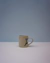 Beige mug with a blue flower design on a light grey background. Tulip Mug | Nerikomi | Fern Taylor | Shop Fodder