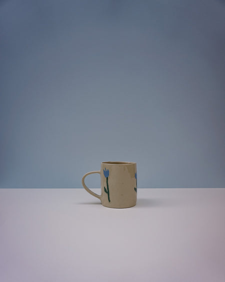 Ceramic mug with floral design on a gradient blue and grey background. Tulip Mug | Nerikomi | Fern Taylor | Shop Fodder