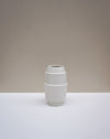 A minimalist white ceramic vase with a stacked, geometric barrel-like design, set against a neutral beige and white studio background. Emma Johnson Ceramics | Fodder | Hope Collection