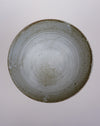 A handmade ceramic bowl with a speckled glaze, photographed from directly above against a neutral light gray background. Scree Ceramics | Fodder | Hope Collection