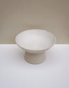 A speckled ceramic pedestal bowl in a warm off-white or cream tone, set against a minimalist beige and white studio background. Scree Ceramics | Fodder | Hope Collection