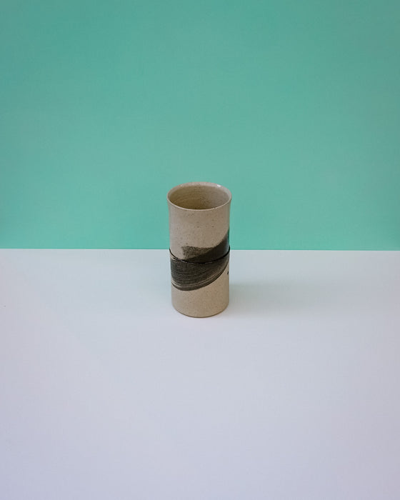 Ceramic vase with black band on a white surface and green background. Janne Meijer Ceramics | Shop Fodder