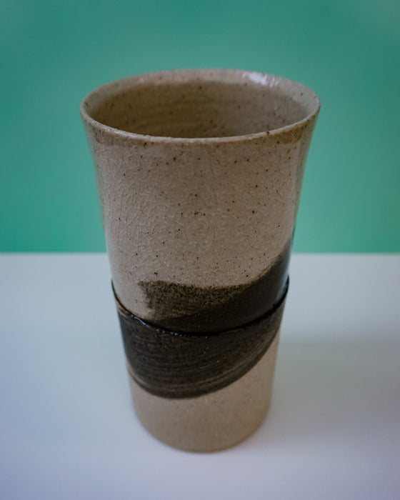 Ceramic vase with black band on a white surface against a green background. Janne Meijer Ceramics | Shop Fodder
