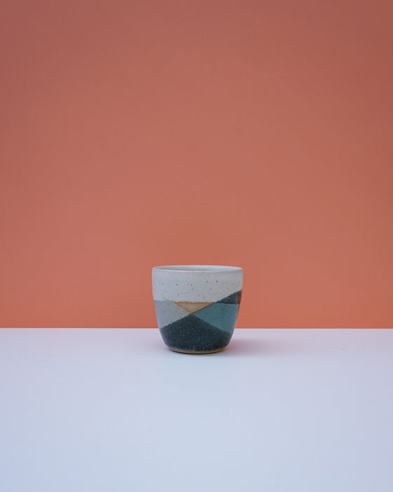 Ceramic cup with geometric design on a peach background. Liz Vidal Ceramics | Shop Fodder