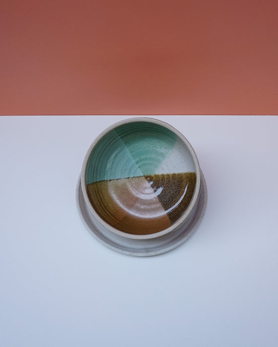 Ceramic dish with gradient colors on a white surface with a pink background. Liz Vidal Ceramics | Shop Fodder