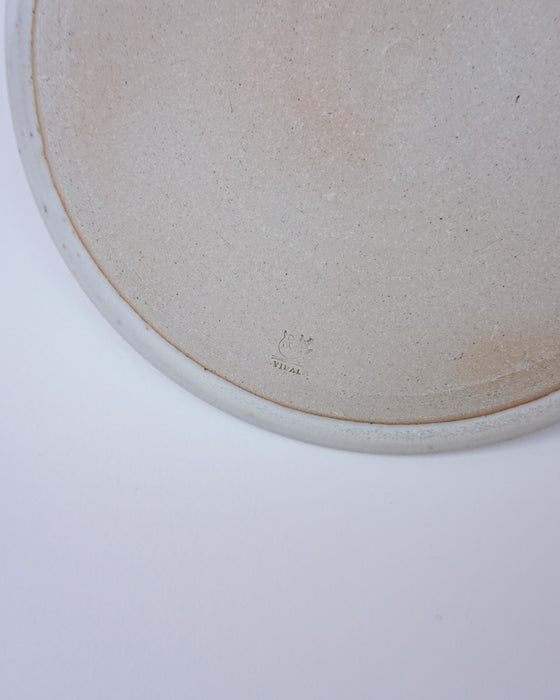 Close-up of a ceramic plate with a logo on a white background. Liz Vidal Ceramics | Shop Fodder