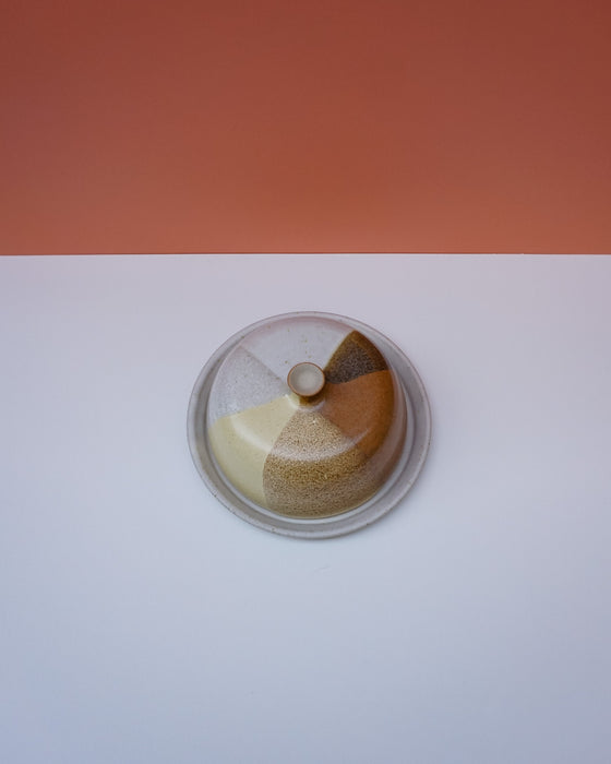 Small cake with a lid on a white surface with an orange background. Liz Vidal Ceramics | Shop Fodder