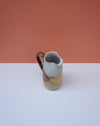 Ceramic pitcher with a gradient design on a white surface and orange background. Liz Vidal Ceramics | Shop Fodder