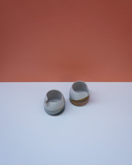 Two ceramic items on a white surface with a red background. Liz Vidal Ceramics | Shop Fodder