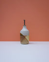Ceramic bottle with geometric design on a peach background. Liz Vidal Ceramics | Shop Fodder