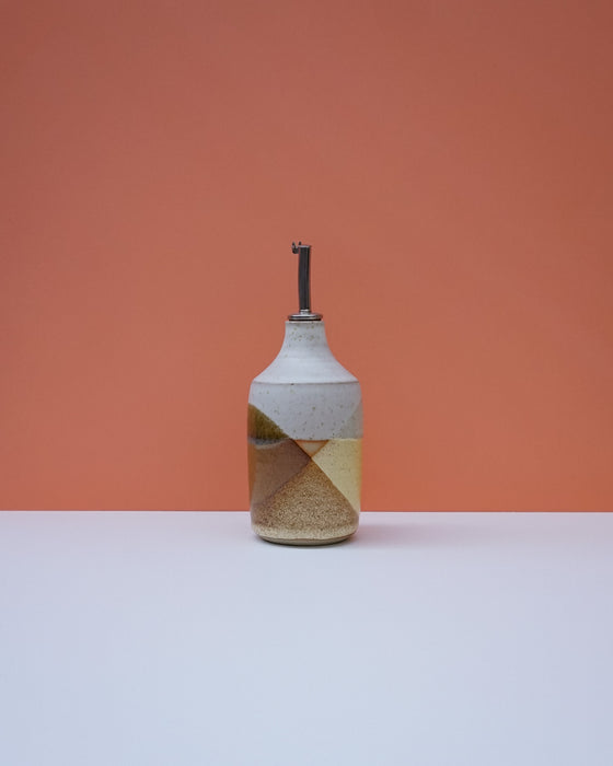 Ceramic bottle with geometric design on a peach background. Liz Vidal Ceramics | Shop Fodder