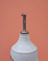 White ceramic bottle with a metal nozzle on an orange background. Liz Vidal Ceramics | Shop Fodder