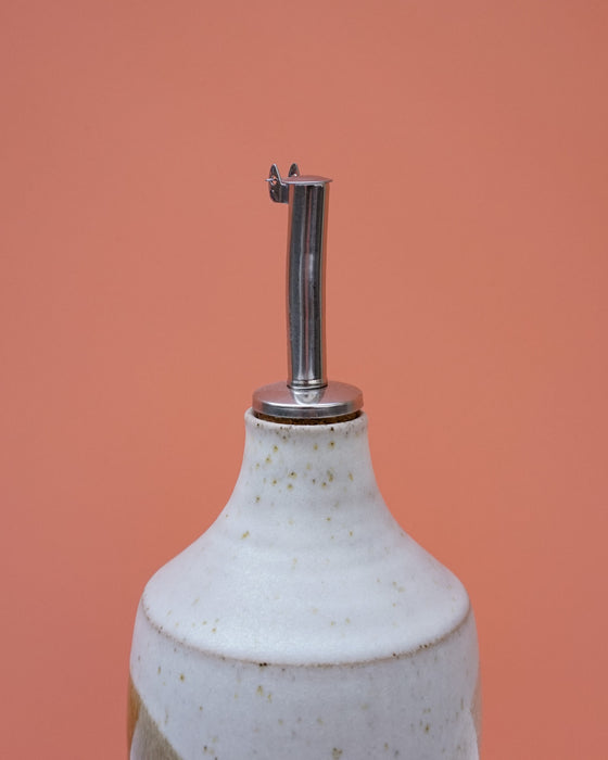 White ceramic bottle with a metal nozzle on an orange background. Liz Vidal Ceramics | Shop Fodder