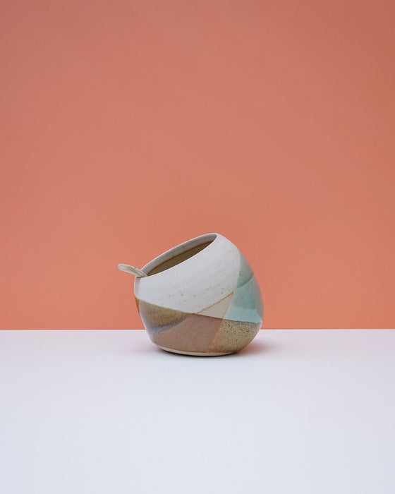 Ceramic pot with geometric design on a peach and white background. Liz Vidal Ceramics | Shop Fodder