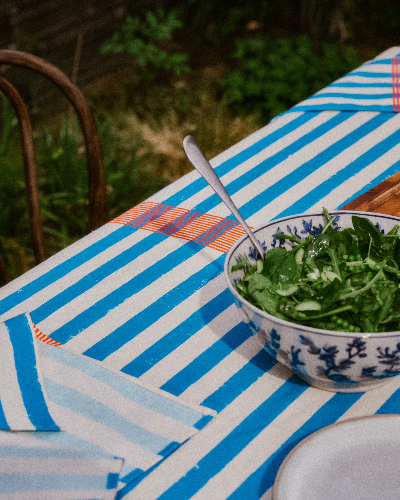 Bowl of salad on a striped tablecloth with a spoon | Fodder_Nic_Brittin_Block_Printed_Lido_Tablecloth_Lunch