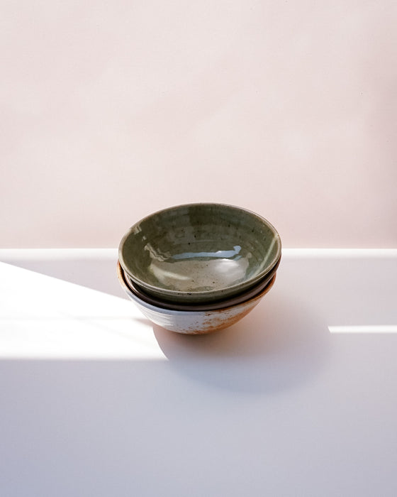 Three nested ceramic bowls with a speckled sage green glaze and a rustic brown rim, set on a white surface with soft natural light. Dinner Bowl | Scree Ceramics | Fodder