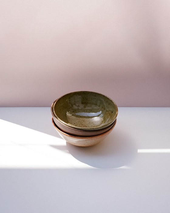 Three stacked ceramic bowls with a speckled green glaze and a speckled beige exterior, set on a white surface against a soft pink background. Morning Bowl | Scree Ceramics | Fodder