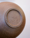 Close-up of the bottom of a brown ceramic vessel, showing a textured stoneware surface and a stamped maker's mark reading 'SCREE' on a light gray background. Morning Bowl | Scree Ceramics | Fodder